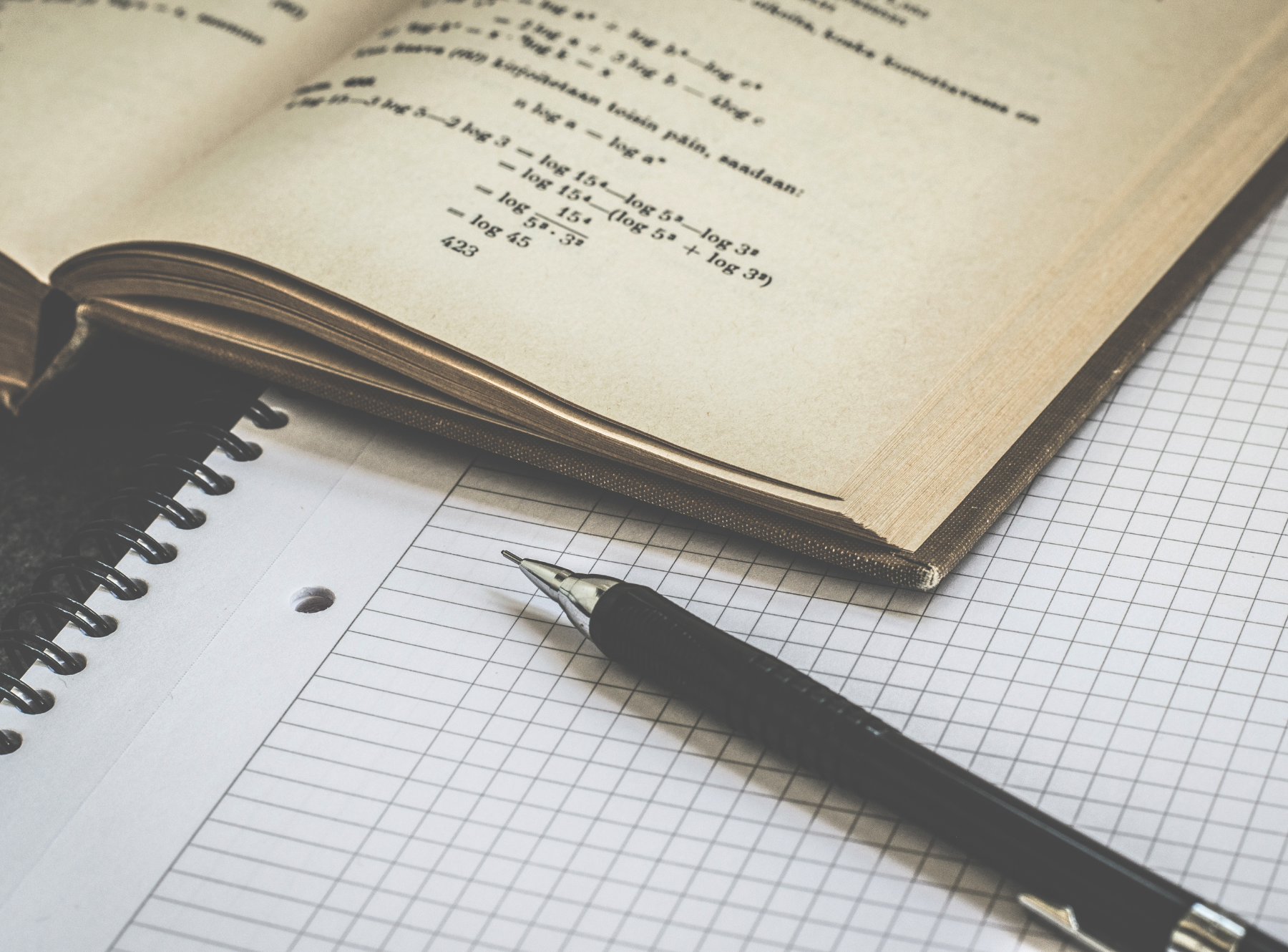 Open book on top corner of notebook with black pen on top of notebook