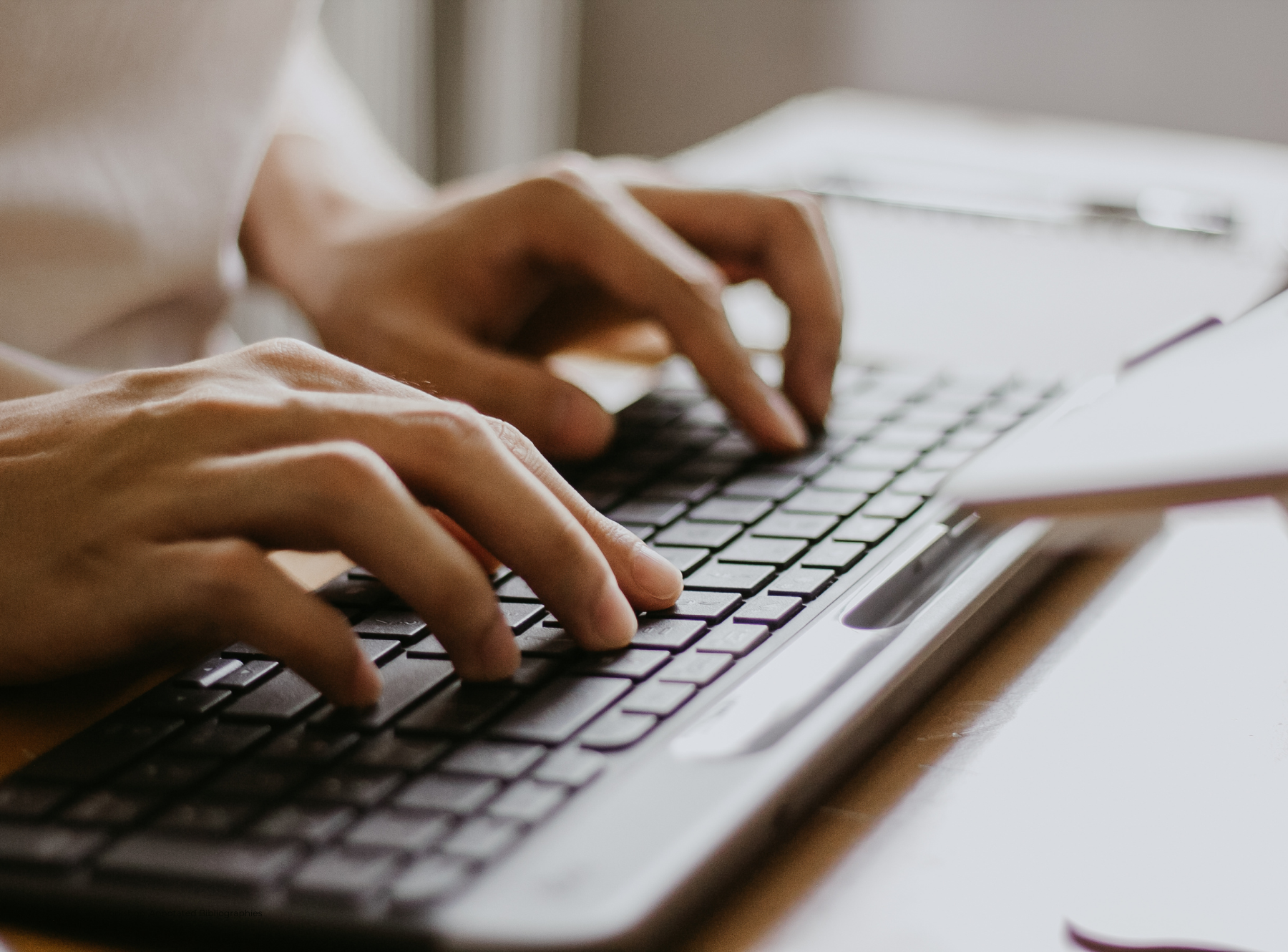 Hands typing on laptop keyboard