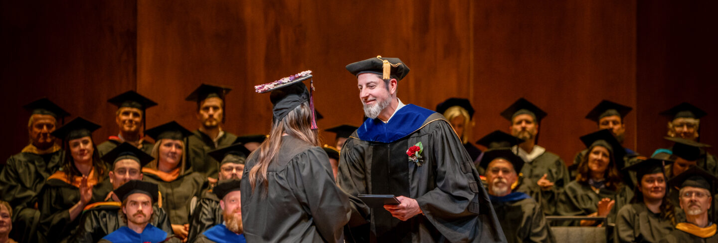 A student receives congratulations from staff at the graduation ceremony.