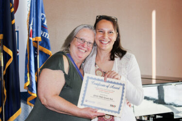 Student and staff member smiling and holding up a grant certificate.