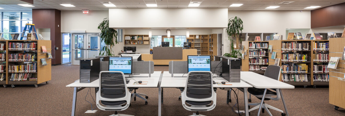 Interior view of Flathead Valley Community College library with computer workstations and bookshelves.