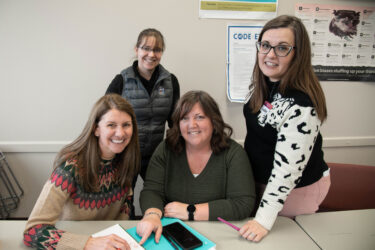 Four committee members at Flathead Valley Community College smiling and working together at a table.